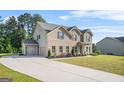 Suburban home features a brick and siding exterior, a three-car garage, and a well-manicured lawn at 361 Traditions Lane, Hampton, GA 30228