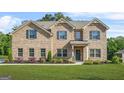 Charming two-story brick home with landscaped yard, complemented by dark shutters and a welcoming front entrance at 361 Traditions Lane, Hampton, GA 30228