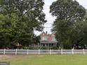 Classic home framed by mature trees and a white picket fence, offering timeless charm and curb appeal at 435 Jackson St, Locust Grove, GA 30248