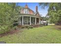 Traditional home with covered porch, columns, brick details, and ample yard space, surrounded by trees and greenery at 435 Jackson St, Locust Grove, GA 30248