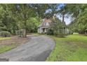 Traditional home with a circular driveway and ample yard space, surrounded by mature trees and lush greenery at 435 Jackson St, Locust Grove, GA 30248