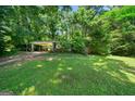 Exterior view of a home with a covered driveway and spacious front yard, surrounded by mature trees at 2257 Chestnut Log Loop, Lithia Springs, GA 30122