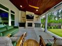 Relaxing covered patio featuring an outdoor fireplace, comfortable seating, ceiling fans, and a view of the backyard at 247 Widener Way, Peachtree City, GA 30269
