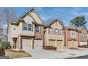 View of the brick exterior of townhomes featuring attached garages and professionally maintained landscaping at 180 Oakland Hills Way, Lawrenceville, GA 30044