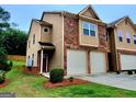 Inviting townhome featuring a two-car garage, tidy landscaping, and a mix of brick and siding for a modern feel at 180 Oakland Hills Way, Lawrenceville, GA 30044