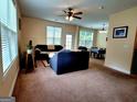 A cozy living room with plush seating, a ceiling fan, and a view into the dining area at 180 Oakland Hills Way, Lawrenceville, GA 30044