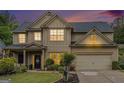 Charming two-story home with a well-manicured lawn, beautiful landscaping and a two car garage at dusk at 230 Haleys Ct, Woodstock, GA 30188