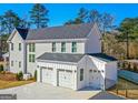 View of attached three car garage featuring white garage doors, siding and black gutters at 915 Laurel Brooke Ave, Peachtree City, GA 30269