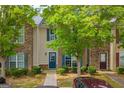 Inviting townhome featuring stone and brick accents, front yard with lush trees and landscaping at 1851 Grove Way, Hampton, GA 30228