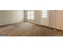 Spacious living room featuring neutral-colored walls, a large window, and a door at 1851 Grove Way, Hampton, GA 30228