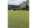 Expansive front yard featuring healthy lawn, manicured shrubbery, and mature trees at 2360 Barrington Trace Sw Cir, South Fulton, GA 30331