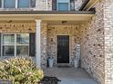 Inviting front porch with brick facade, dark door, and potted plants, creates a welcoming entrance at 10736 Southwood Dr, Hampton, GA 30228