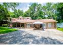 Sprawling tan and brick home with multiple entrances and front porch surrounded by lush green trees at 258 Big Oak Rd, Whitesburg, GA 30185