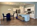 Kitchen and dining area with stainless steel appliances, granite island, and wooden floors at 340 Mcgiboney Ln, Covington, GA 30016