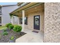 Close up of the front porch with brick facade, decorative shrubs and a welcoming front door at 9046 Holder Rd, Locust Grove, GA 30248