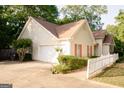 Home with a white garage door, red shutters, complemented by a white picket fence and driveway at 110 Orchard Vw, Fayetteville, GA 30215