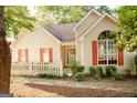 Charming home featuring a white picket fence, complemented by trees and light-colored siding with red shutters at 110 Orchard Vw, Fayetteville, GA 30215