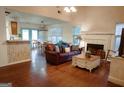 Cozy living room with hardwood floors, a fireplace, and a comfortable leather sofa, leading to the dining area at 110 Orchard Vw, Fayetteville, GA 30215