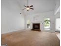 Spacious living room with a fireplace, ceiling fan, and large windows with natural light at 474 Strawberry Walk, Loganville, GA 30052
