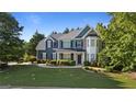 Two-story home boasts manicured lawn, stylish blue siding, dark shutters, and stone accents at 1210 Magnolia Park Cir, Cumming, GA 30040