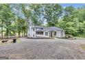 Elegant white home with black roof and trim, featuring a screened-in porch and mature trees at 6290 Cascade Palmetto Hwy, Fairburn, GA 30213