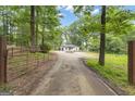 Charming white home nestled in a wooded lot, framed by a gated driveway and lush trees at 6290 Cascade Palmetto Hwy, Fairburn, GA 30213