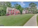 Beautifully landscaped front yard with brick home and mature trees in background at 165 Hidden Lake Dr, Fayetteville, GA 30215
