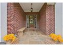 Charming front porch with brick accents, wooden bench, and decorative floral arrangements creating a cozy entrance at 1535 Lake Dow Rd, Mcdonough, GA 30252