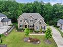 Aerial view of a brick home with a manicured lawn, garden beds, and mature trees in a desirable neighborhood at 3525 Montebello Pkwy, Cumming, GA 30028