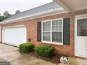 Lovely brick home featuring an attached garage, black shutters and landscaped garden at 165 Woodgate Cir, Fayetteville, GA 30214