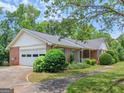 Side view of a brick house with an attached garage and a paved driveway, surrounded by lush greenery at 114 Overlook Dr, Mcdonough, GA 30252