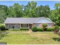 Inviting single-story home featuring a brick facade, tidy landscaping, and a serene, tree-lined backdrop at 114 Overlook Dr, Mcdonough, GA 30252
