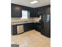 Efficient kitchen featuring black cabinets, tile floors, stainless steel dishwasher, and matching appliances at 1321 Lakeview Nw Dr, Conyers, GA 30012