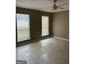 A spacious living room with tile floors, neutral walls, and two large windows for natural light at 1321 Lakeview Nw Dr, Conyers, GA 30012