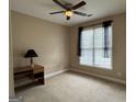 Neutral bedroom with a ceiling fan, large window, and a desk area, ready for personalization at 1031 Jordan Rd, Dacula, GA 30019