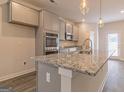 A kitchen island features granite countertops, with gray cabinets and modern fixtures at 132 Post Oak Dr St, Jackson, GA 30253