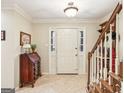 Bright foyer with tiled floor, staircase, and decorative writing desk at 1386 Sheffield Glen Ne Way, Atlanta, GA 30329
