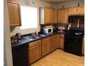 Kitchen with wood cabinets, dark countertops, black appliances, and wood floors at 5658 Wind Gate Ln, Lithonia, GA 30058