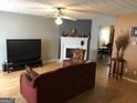 Open living room with a fireplace, ceiling fan, hardwood floors, and dining area at 5658 Wind Gate Ln, Lithonia, GA 30058
