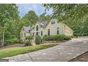 Elegant home featuring lush landscaping, a winding driveway, and an attached garage at 5940 Plantation Dr, Roswell, GA 30075