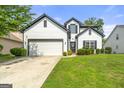 Charming home features a manicured lawn, two-car garage, and classic white siding with black trim details at 1535 Fenmore St, Lithia Springs, GA 30122