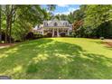 Traditional home with a manicured lawn and mature trees, under a sunny blue sky at 220 Broadmoor Dr, Fayetteville, GA 30215