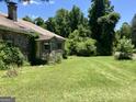 Side exterior view of an abandoned property with a stone facade and overgrown lawn at 72 N Pomona N Rd, Hampton, GA 30228