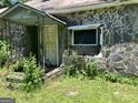 Close-up of the exterior showing a stone facade, porch, door and broken window at 72 N Pomona N Rd, Hampton, GA 30228