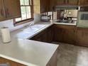 Traditional kitchen featuring wood cabinets, a double basin sink, and a view to the living room at 5125 Flakes Mill Rd, Ellenwood, GA 30294