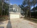 Two-story home featuring a gray facade, a brick-accented front, and an attached two-car garage with a long concrete driveway at 142 Tye St, Stockbridge, GA 30281