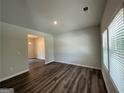 Bright living room featuring hardwood floors, neutral walls, and a window offering natural light; a doorway leads to another room at 142 Tye St, Stockbridge, GA 30281
