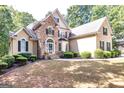 Elegant two-story home featuring stone and stucco exterior, a well-manicured lawn, and tidy shrubbery at 235 Ashley Forest Dr, Fayetteville, GA 30214
