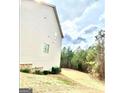 View of the home from the side angle, showing the spacious yard and surrounding trees at 413 Atlas Ct, Locust Grove, GA 30248