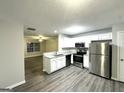 Bright kitchen featuring stainless steel appliances, white cabinets, and gray laminate flooring at 408 Kendall Ln, Mcdonough, GA 30253